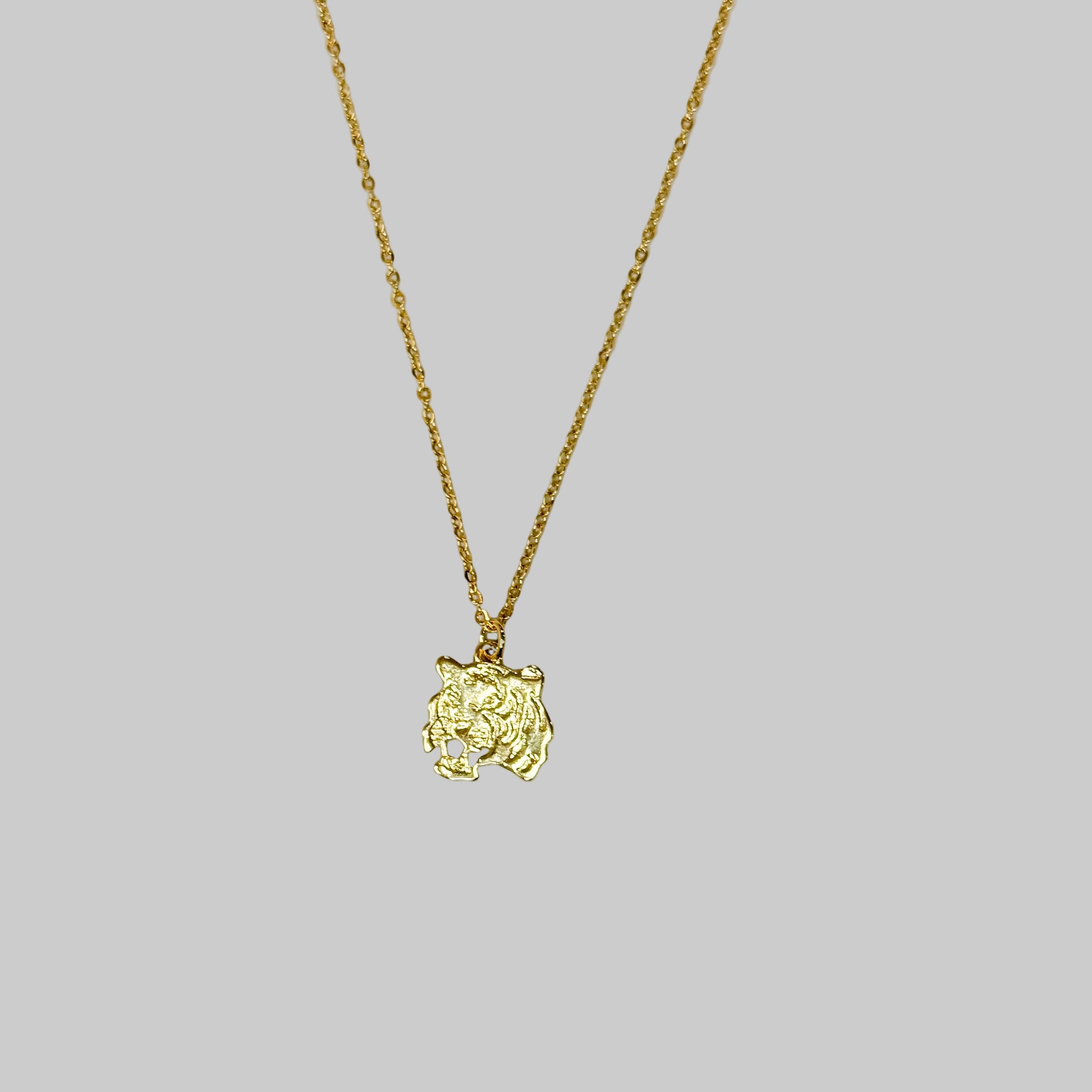 Gold necklace with a small pendant on a light gray background