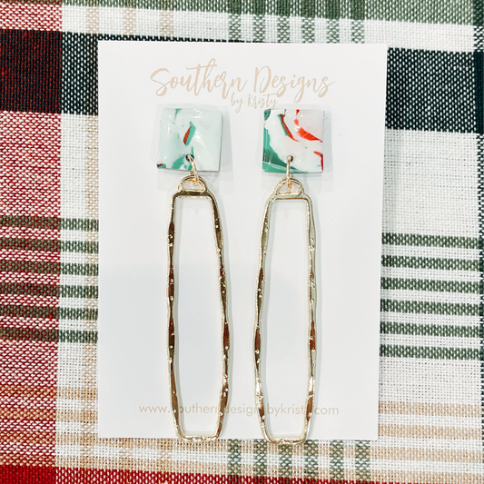 A pair of long dangle earrings with a gold-tone metal hook and a multicolored geometric pattern on the earring post.