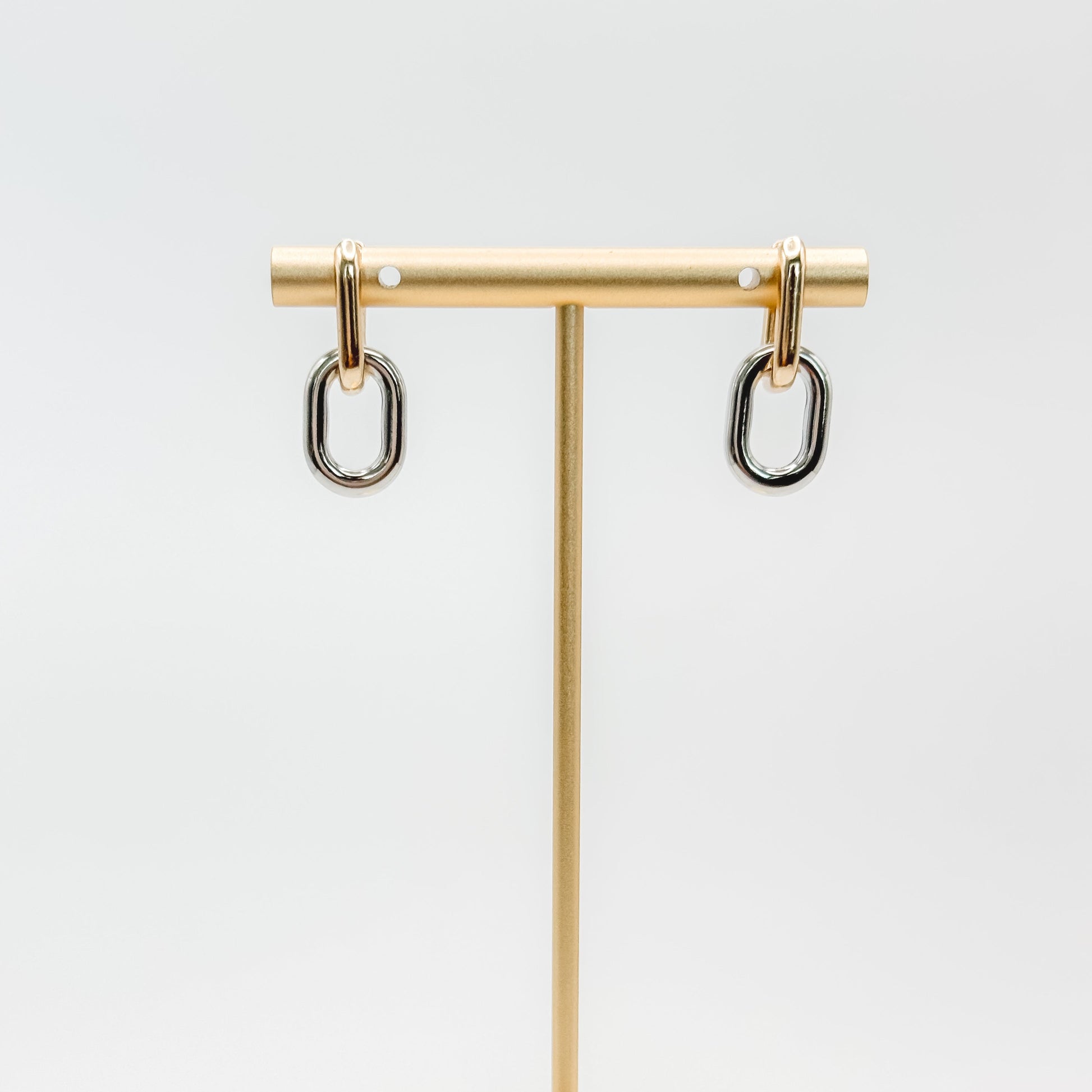 Gold jewelry stand with two earrings on a white background