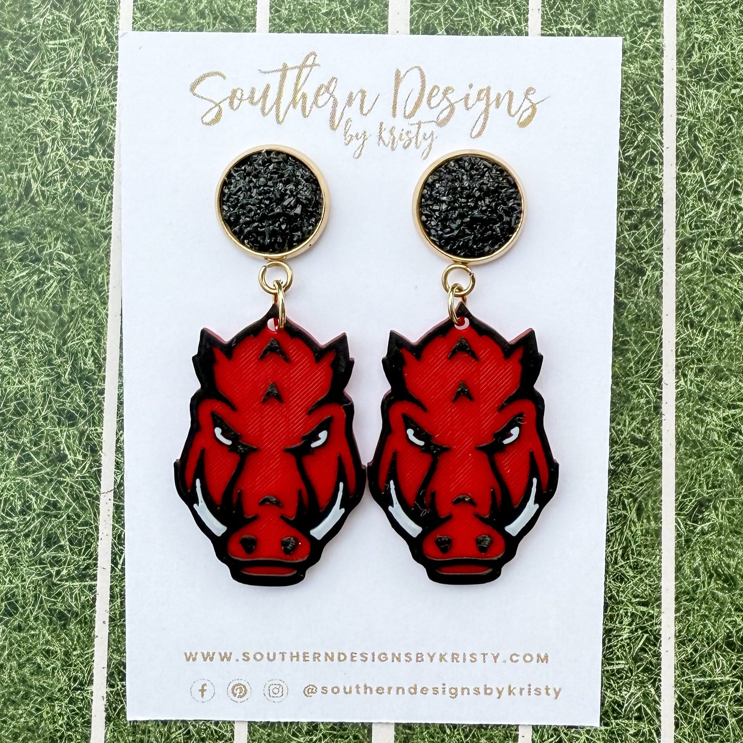 Red and black animal head earrings on a white card with 'Southern Designs by Kristy' branding, against a green and white striped background.