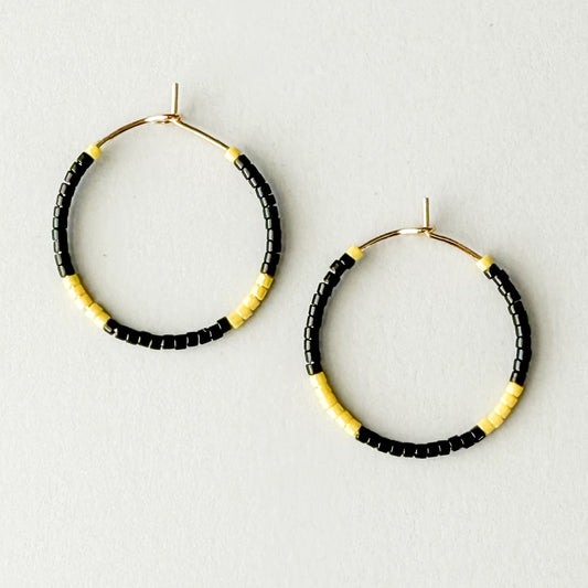 Hoop earrings with black and yellow beads on a light gray background