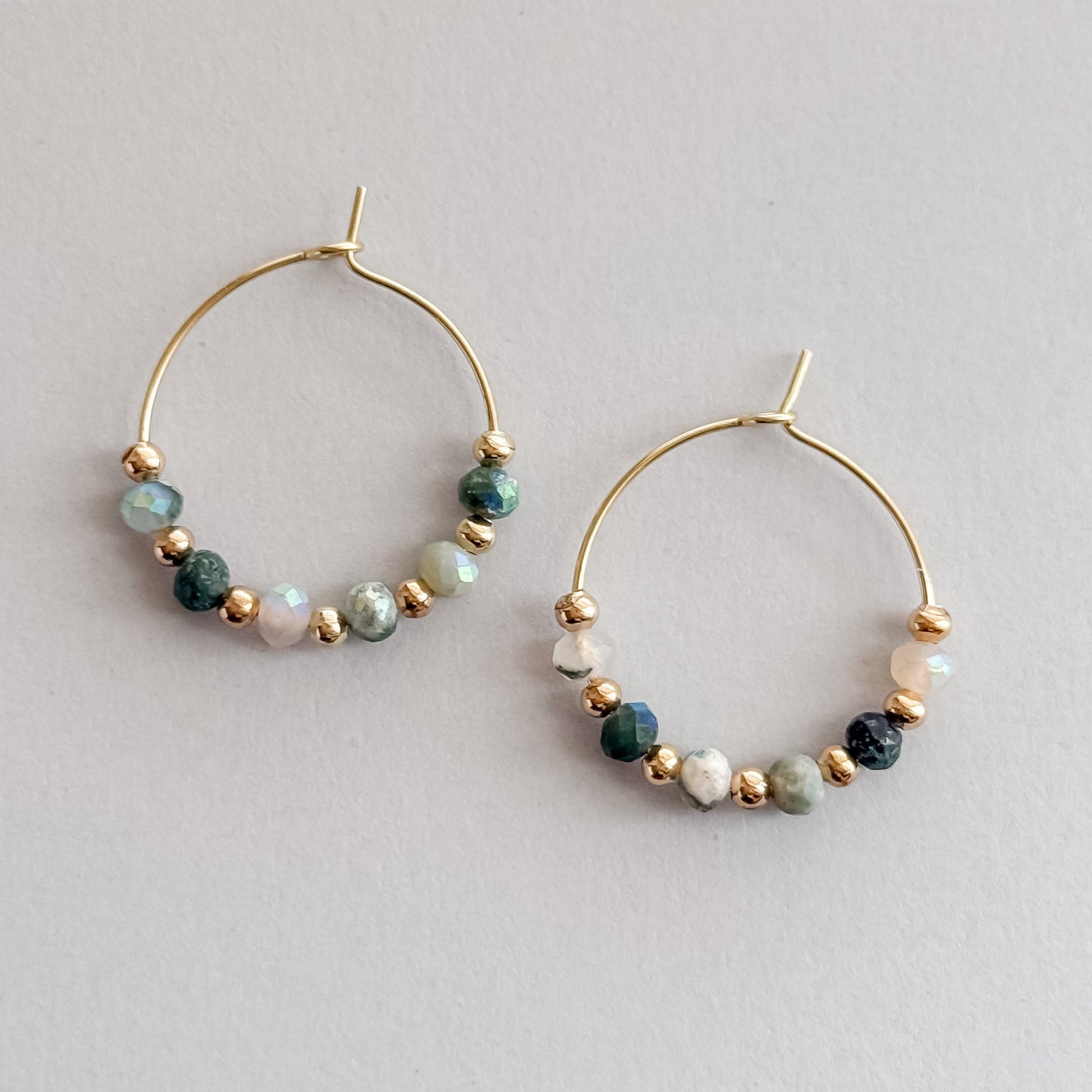 Gold hoop earrings with beaded accents on a light gray background