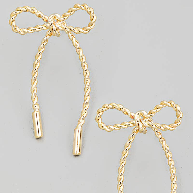 A pair of gold-colored twisted bow tie earrings with attached rope-like cords.