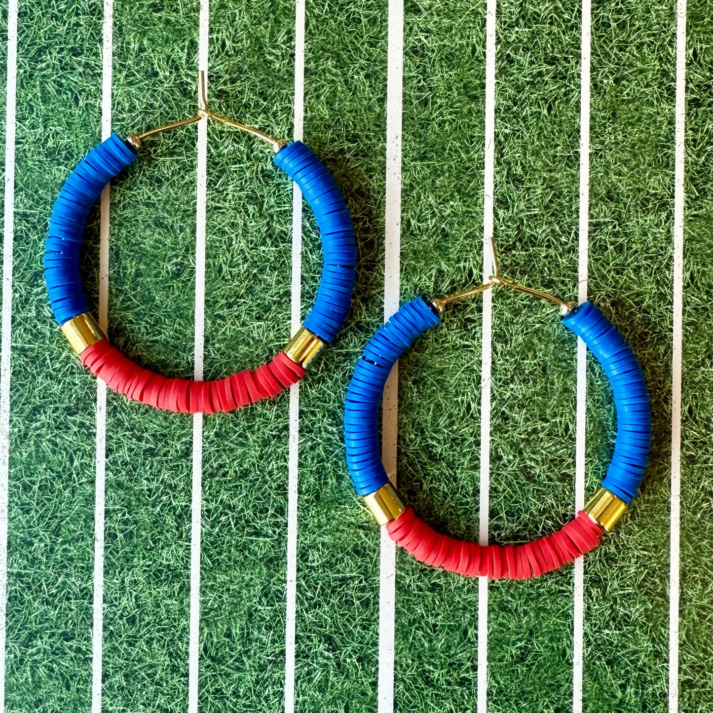 Hoop earrings with blue, red, and gold accents on a green and white striped background