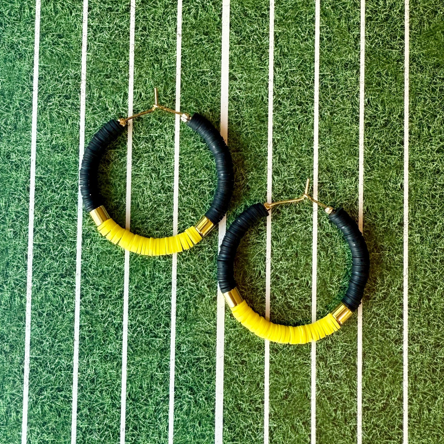 Black and yellow hoop earrings on a green and white striped background