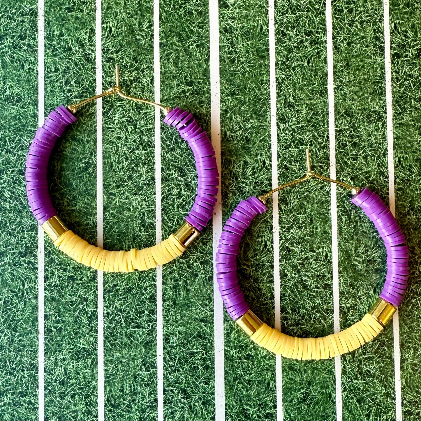 Purple and gold hoop earrings on a green and white striped background