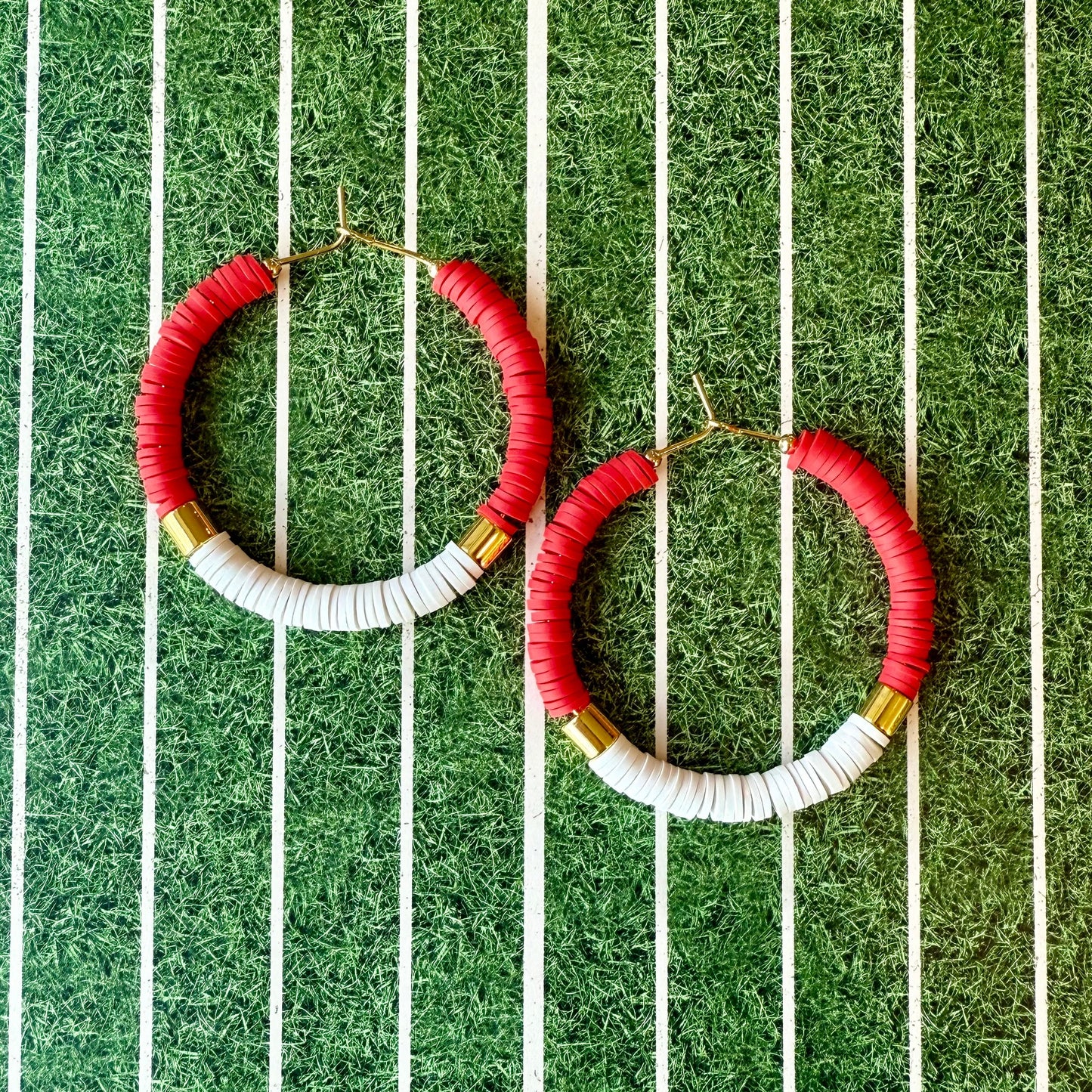 Red and white beaded hoop earrings on a green and white striped background