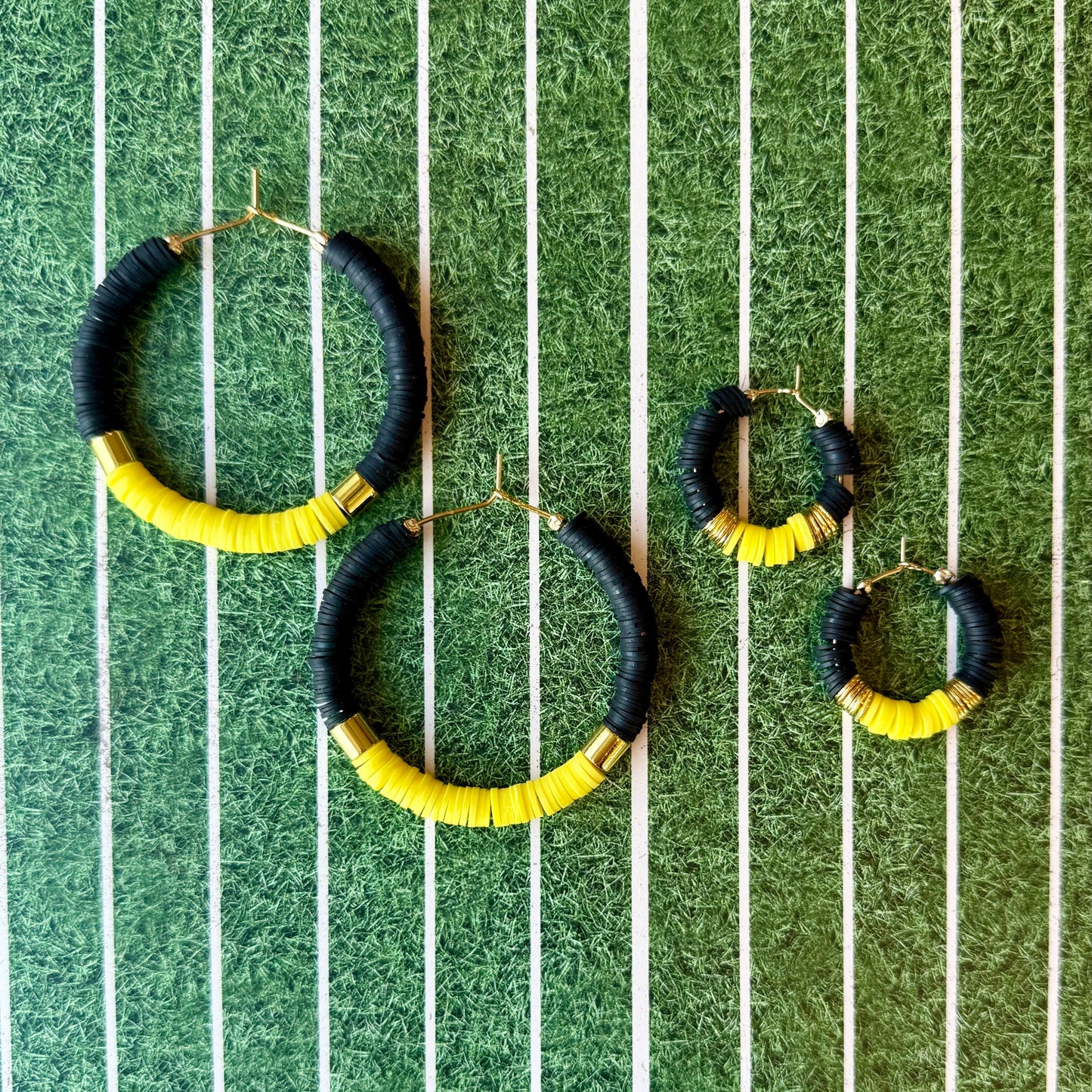 Black and yellow hoop earrings on a green and white striped background